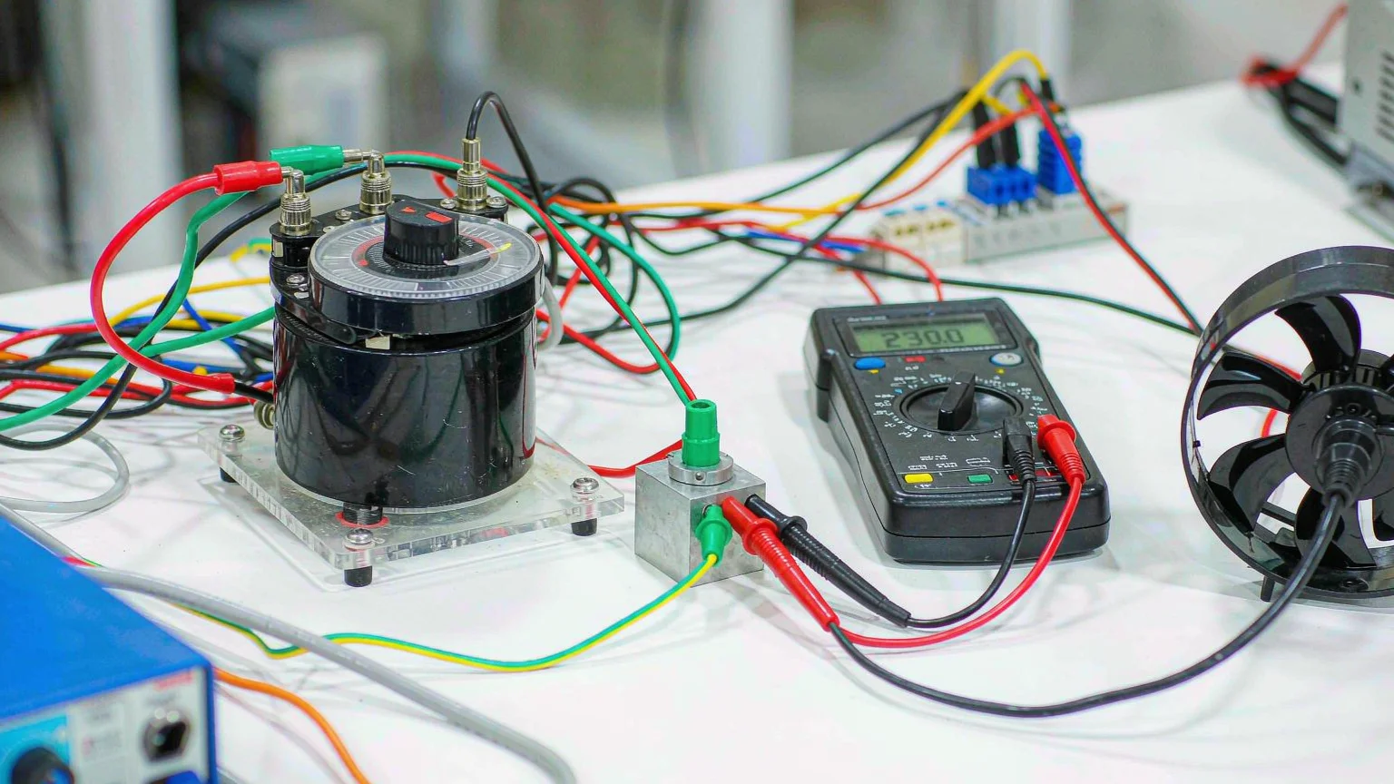 Bench setup showing a variable transformer variac wired to a test load with a multimeter and clamp meter